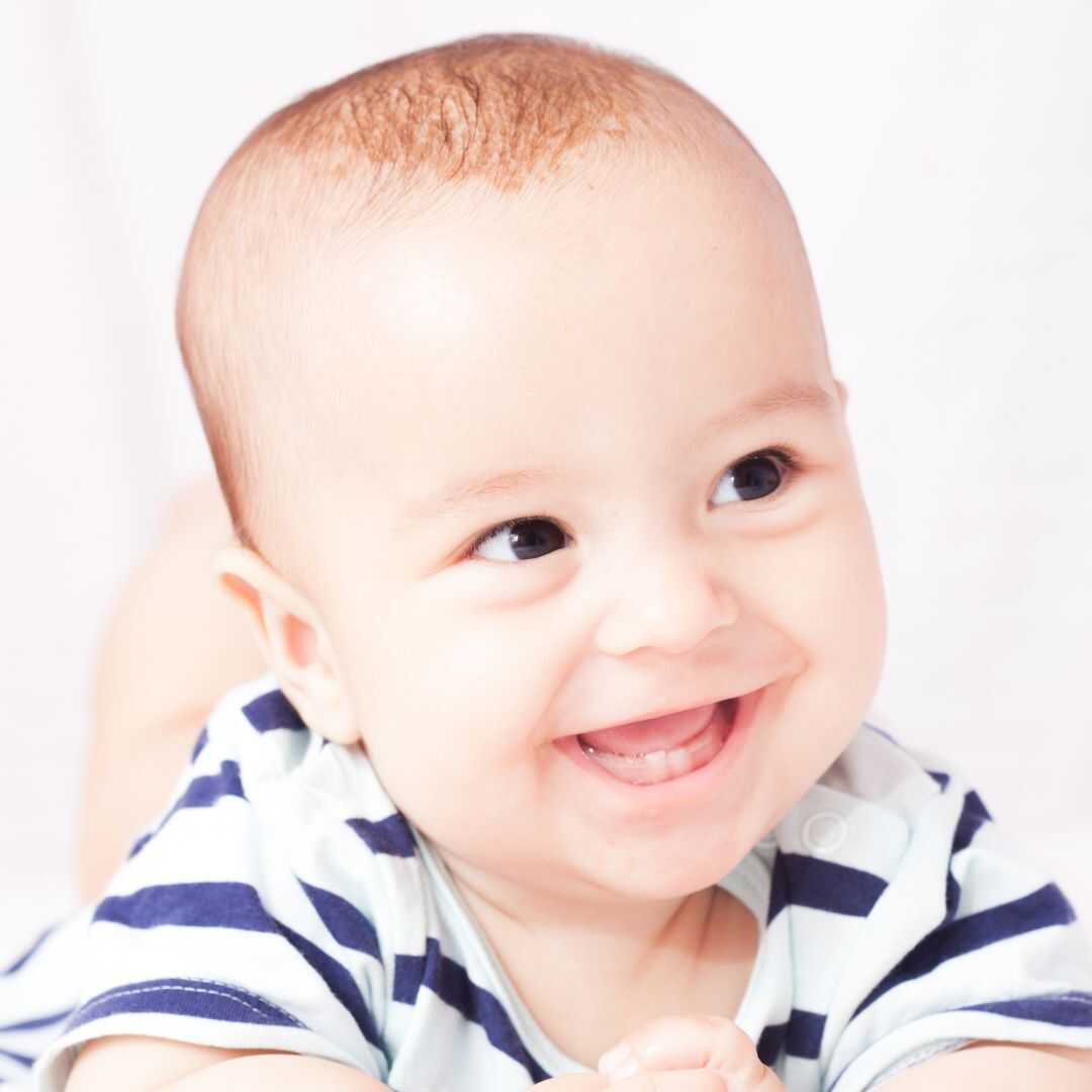 A smiling infant with the first lower teeth just visible