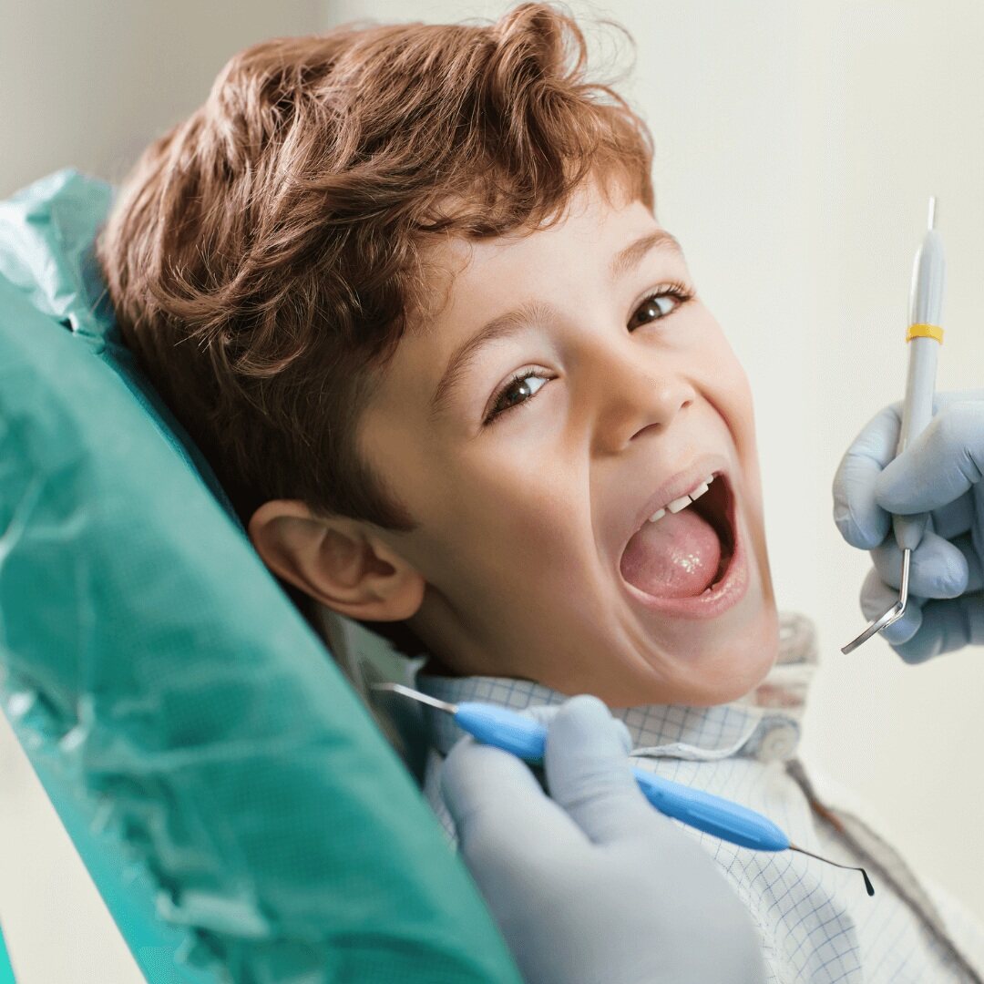 A young boy opening wide in the dental chair during a check-up