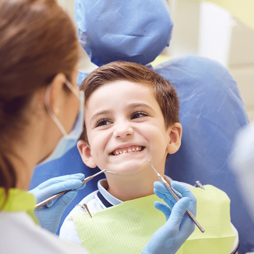 A smiling child in a dental bib as the dentist prepares to examine his teeth