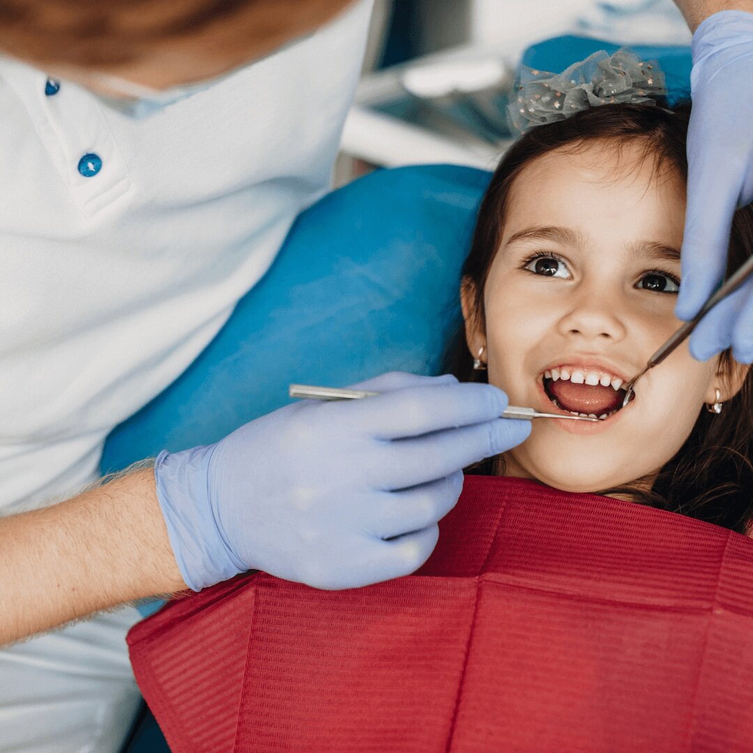A young girl having her teeth examined with a mirror and probe