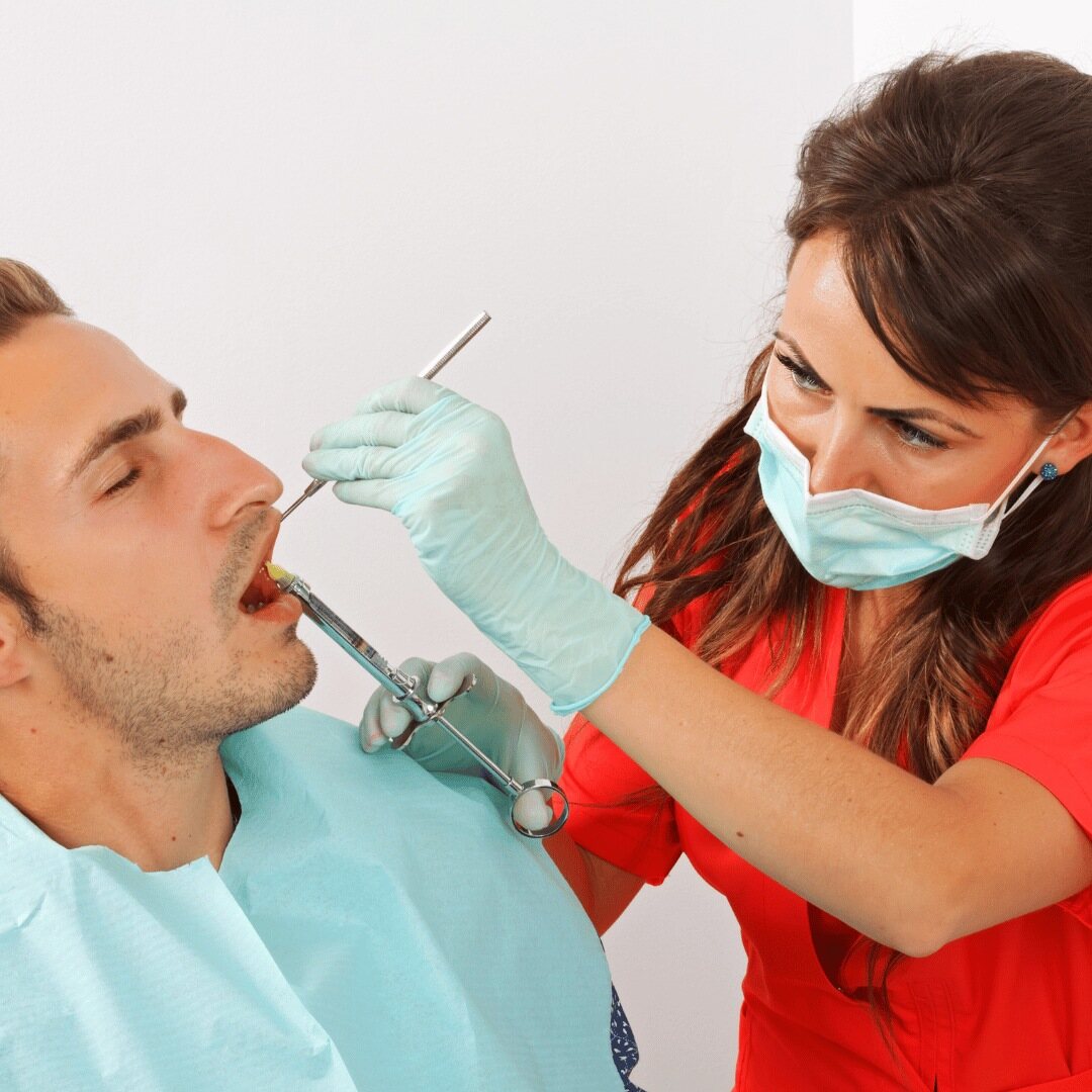 A patient being treated while the dentist works with a mirror and syringe