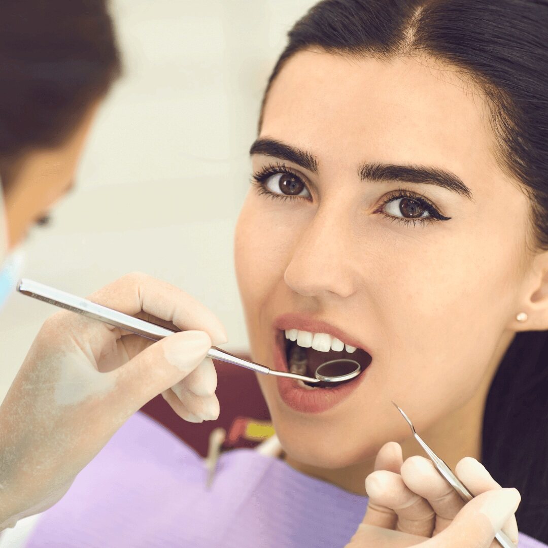 A patient's teeth being checked with a mirror and probe at a routine examination