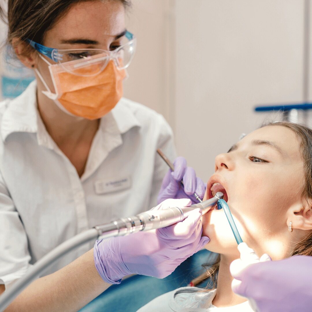 A dentist using suction while treating a patient in the clinic