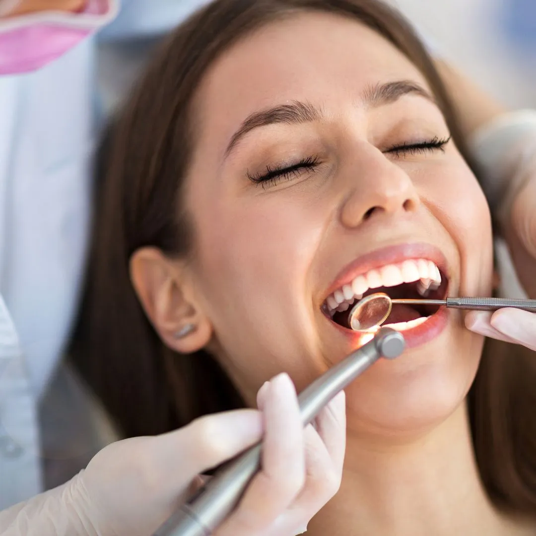 A patient having her teeth cleaned with a scaler and mirror