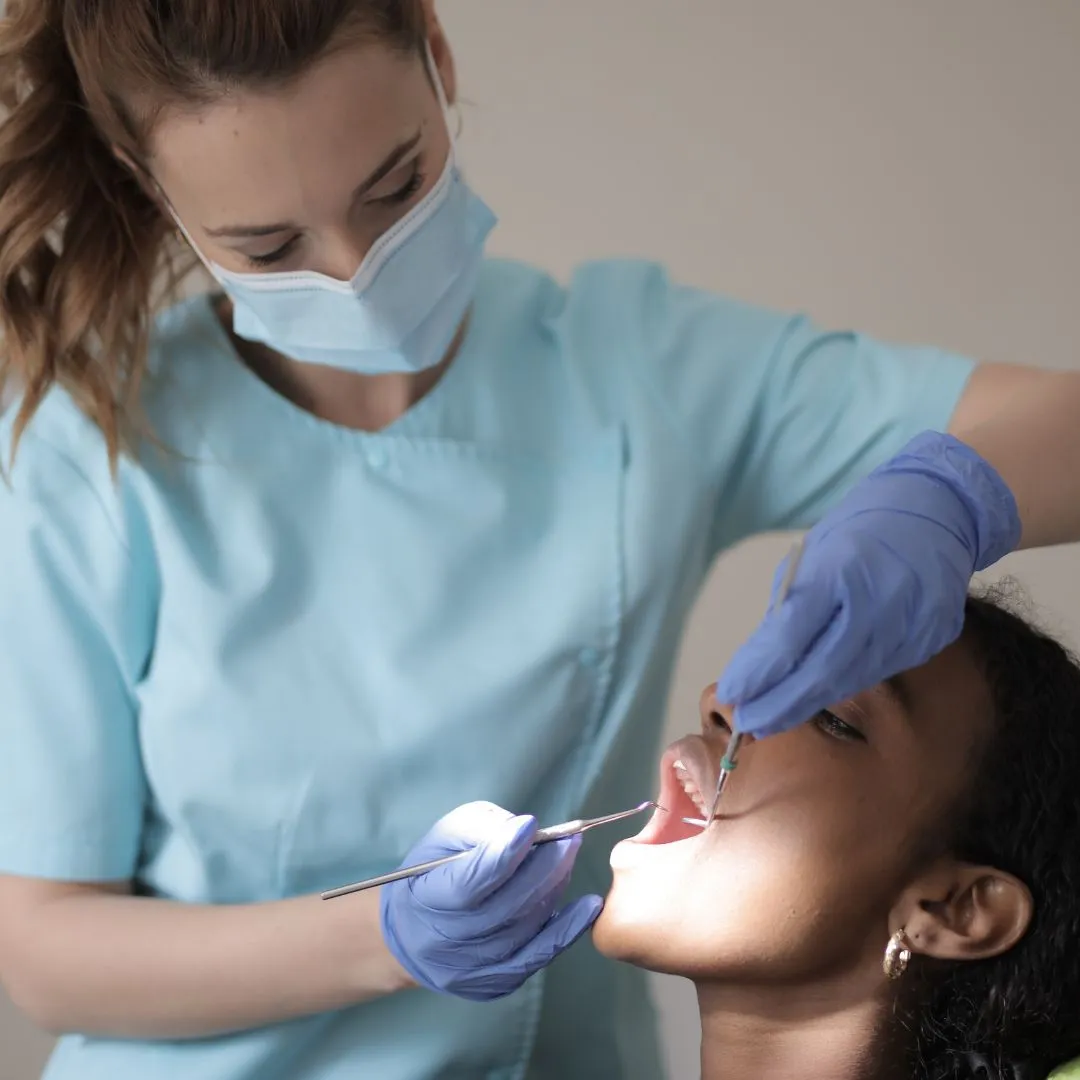 A hygienist scaling a patient's teeth during a professional cleaning