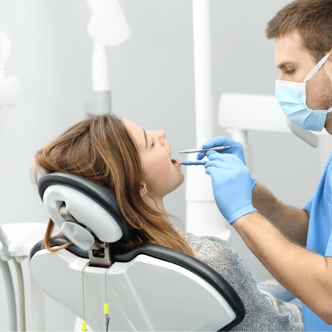 A patient reclined in the dental chair while the dentist examines her teeth