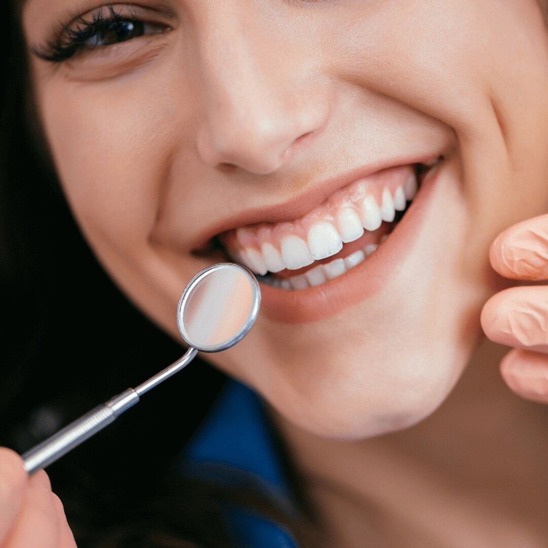 A dental mirror held beside a patient's smile after professional whitening
