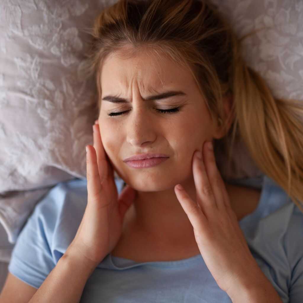 A woman pressing both jaw joints in discomfort