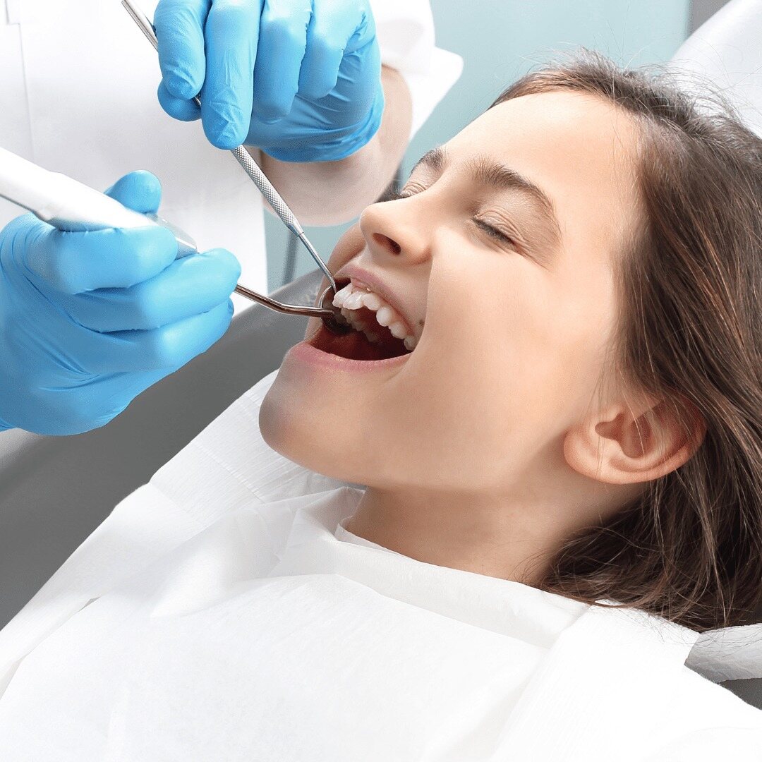 A patient reclined while the endodontist works with suction and an instrument