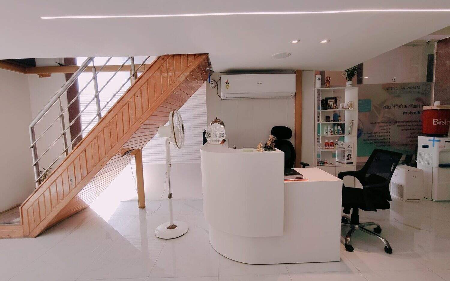 The reception desk at Mahavirai Dental and Medical Care, with the staircase and product display behind